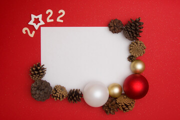 Christmas layout on a red background. New Year card with white sheet for text, with numbers 2022,...