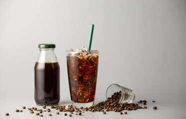 Iced americano coffee with coffee beans on grey background, Black coffee glass package for takeaway. Cold beverage product.