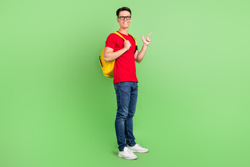 Photo of funny pretty young guy dressed red t-shirt glasses pointing finger empty space smiling...