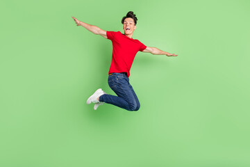 Fototapeta na wymiar Full size profile side photo of young guy happy smile air flu jump hands wings isolated over green color background