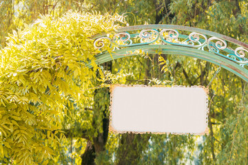 The entrance to a natural park or botanical garden with a vintage arch and ivy, on the gate hangs an empty sign