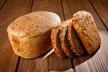 A loaf of delicious white bread made from natural products, on hops with flax saturation, without baker's yeast, on a wooden table surface.