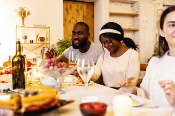 Happy Thanksgiving dinner party with family and friends with turkey and holiday traditional food, dishes on table.