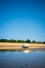A motorboat laying on the beach at lowtide on a sunny summertime on the Isle of île de re in the...