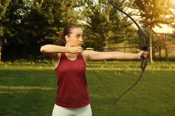 Woman with bow and arrow practicing archery in park
