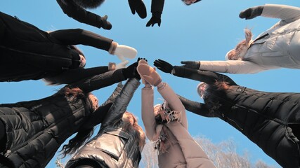 Girls friends join hands in the center on a winter day.