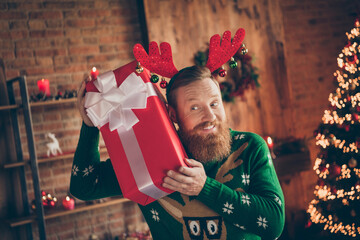 Portrait of attractive cheerful curious guy holding giftbox eve day december at modern loft industrial style indoors
