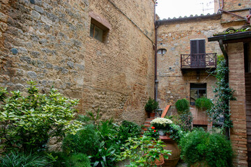 Innenhof mit Grünpflanzen in der Altstadt von San Gimignano - obrazy, fototapety, plakaty