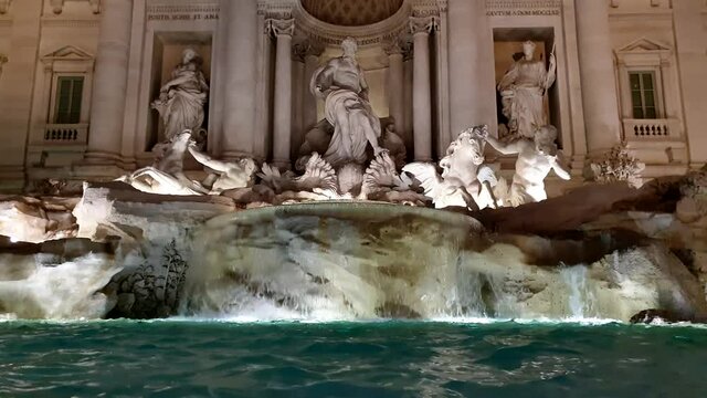 Low-angle pov of Fontana di Trevi fountain in Rome illuminated at night. Italy