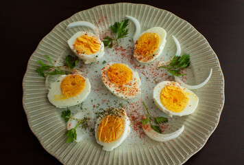 Boiled egg on a plate decorated with parsley leaves, onions and spices.