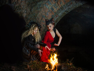 Witches conjure by the fire on Halloween night. Ghost girls.