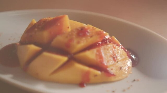 Plate of chopped mango with Mexican chamoy sauce and blurry background