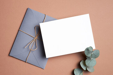 Greeting or invitation card mockup with envelope and natural eucalyptus twig