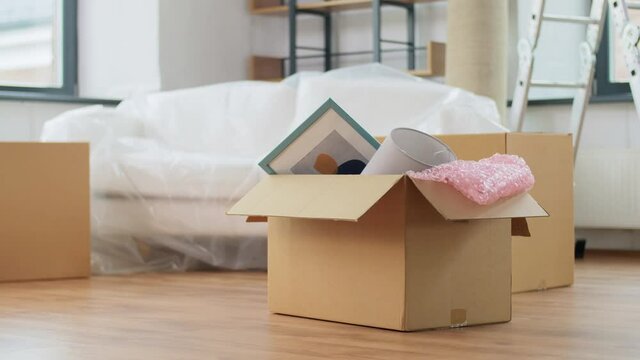 moving, repair and real estate concept - box with stuff on floor at new home