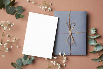 Wedding invitation or greeting card mockup with envelope and eucalyptus and gypsophila twigs.