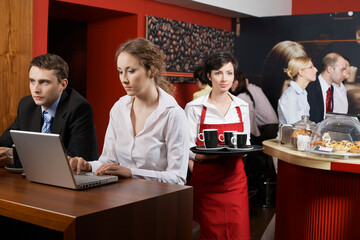 Business people using laptops in coffee shop