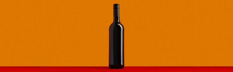 Bottle of red wine on orange and red background. Mock up drink with place for you lable and text
