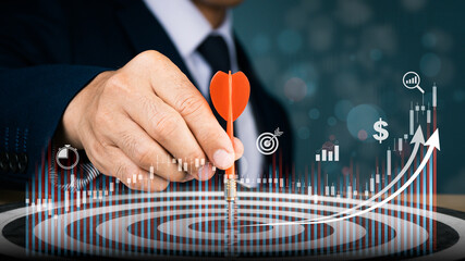 A red dart is being placed into the middle of a circular target in the right hand of a man in a suit. Concep's goal is to attain it.