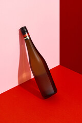 Bottle of wine leaning on the wall. Alcoholic drink on red and pink creative background with deep...