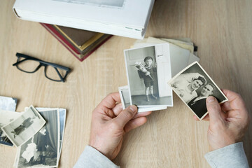 closeup male hand holding old vintage photos of 1940-1950, concept of family tree, genealogy,...