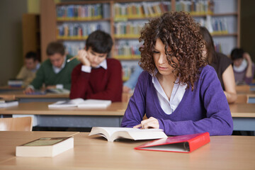Fototapeta na wymiar Students reading books at desks in library