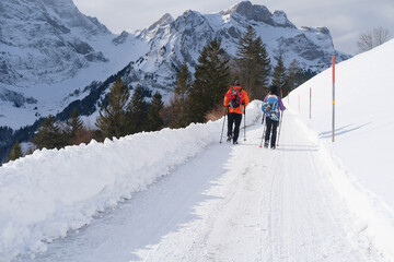 couple young man and woman with backpacks and snowmobiles on their backs walking in alps, hikers admiring mountain winter landscape, Sports Concept, Healthy Lifestyle, Heath and Winter Activity