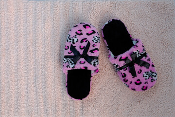 pink domestic slipper for women with black bow stand on the floor on a light plush rug, concept of...