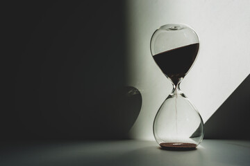 Time is measured by an hourglass in the twilight illuminated by sunlight.