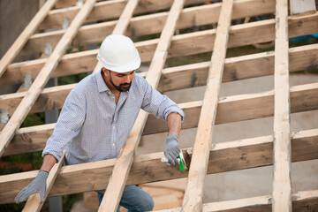 The young builder works on an unfinished roof