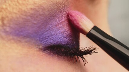 Make-up artist applies makeup to the upper eyelid, close-up.  Makeup artist applies a bright eye shadow with a makeup brush.Tutorial master class of professional makeup. Slow motion cinematic shoot.