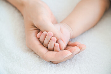 赤ちゃんの手を支えるお母さんの手