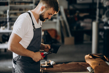 Man tailor working with leather fabric