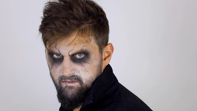a man with undead make-up looks at the camera and turns around