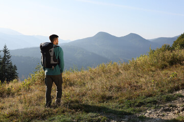 Naklejka na ściany i meble Tourist with backpack in mountains on sunny day, back view. Space for text