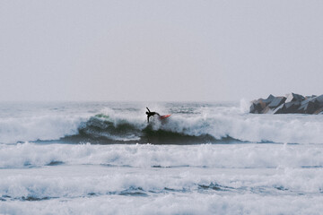 Naklejka premium Fotografía en color de un surfero cayéndose de su tabla de surf tratando de saltar una ola en la playa.