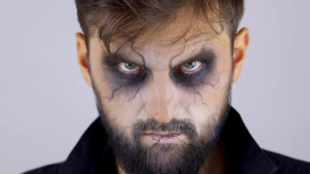 man with make-up for the holiday, Halloween looks at the camera.