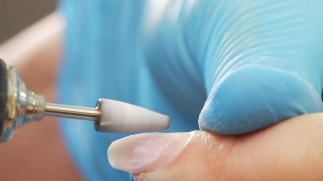 Manicurist removing gel polish or acrylic from nails with the help of a manicure machine. Nail manicure process in a beauty salon. Process of hardware manicure in the salon, Close up 4k video.