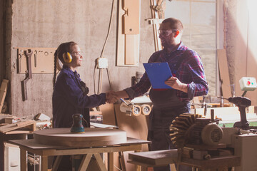 Adult carpenter congratulating teen boy after passing final practical exam