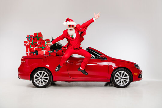 Full length body size view of attractive cheerful Santa jumping near car having fun isolated over grey color background