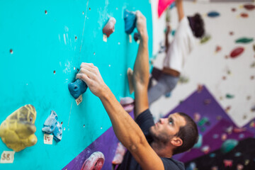 Obraz na płótnie Canvas Handsome athletic men climbing on a indoor climbing wall. Extreme sports concept.