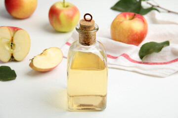 Natural apple vinegar and fresh fruits on white table