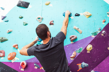 Fototapeta premium Sportsman climber climbing on artificial wall indoors. Extreme sports concept.