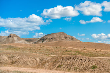 Beautiful landscape of mountainous terrain with hills against a blue sky with clouds