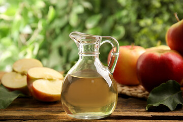 Natural apple vinegar and fresh fruits on wooden table against blurred background