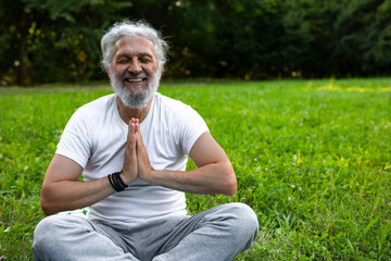 Naklejka na ściany i meble Senior attractive man is practicing yoga in the nature 