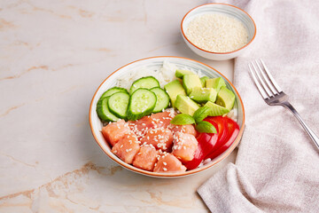 Poke bowl with salmon, rice, avocado, cucumber, pepper and sesame seeds. Hawaiian ahi, a diet meal with fish. Close-up