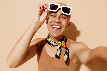 Close up young trendy fashionable blond latin gay man in beige tank shirt neck scarf take off...