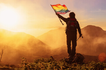 hiker with backpack and trekking poles waving an lgbt pride flag demanding the inclusion and respect of gay people in sport. - obrazy, fototapety, plakaty