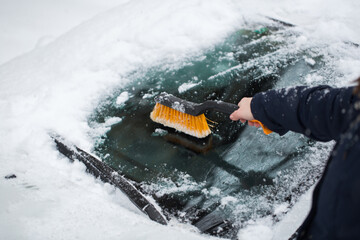 Woman removing snow from car windshield