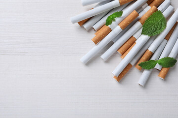Menthol cigarettes and mint on white wooden table, flat lay. Space for text